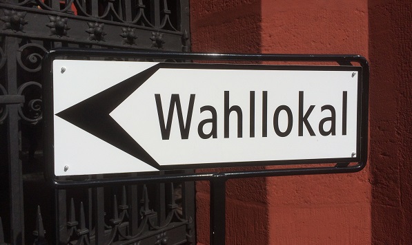 Ein mit "Wahllokal" angeschriebenes Schild weist den Weg.